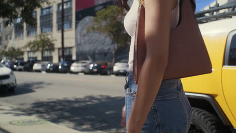 back view girl walking alone near city road. asian woman going on sidewalk.