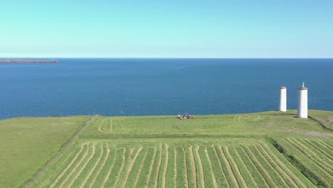 El-Tractor-Trabaja-En-Un-Vibrante-Campo-Agrícola-Verde-Cerca-De-Las-Torres-De-Navegación-Marina.