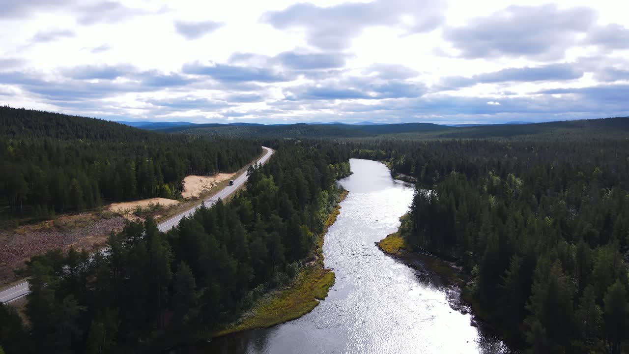 Auto valtatiellä Lapissa Inarijärven rannalla, metsien ympäröimänä, Inari, Suomi.