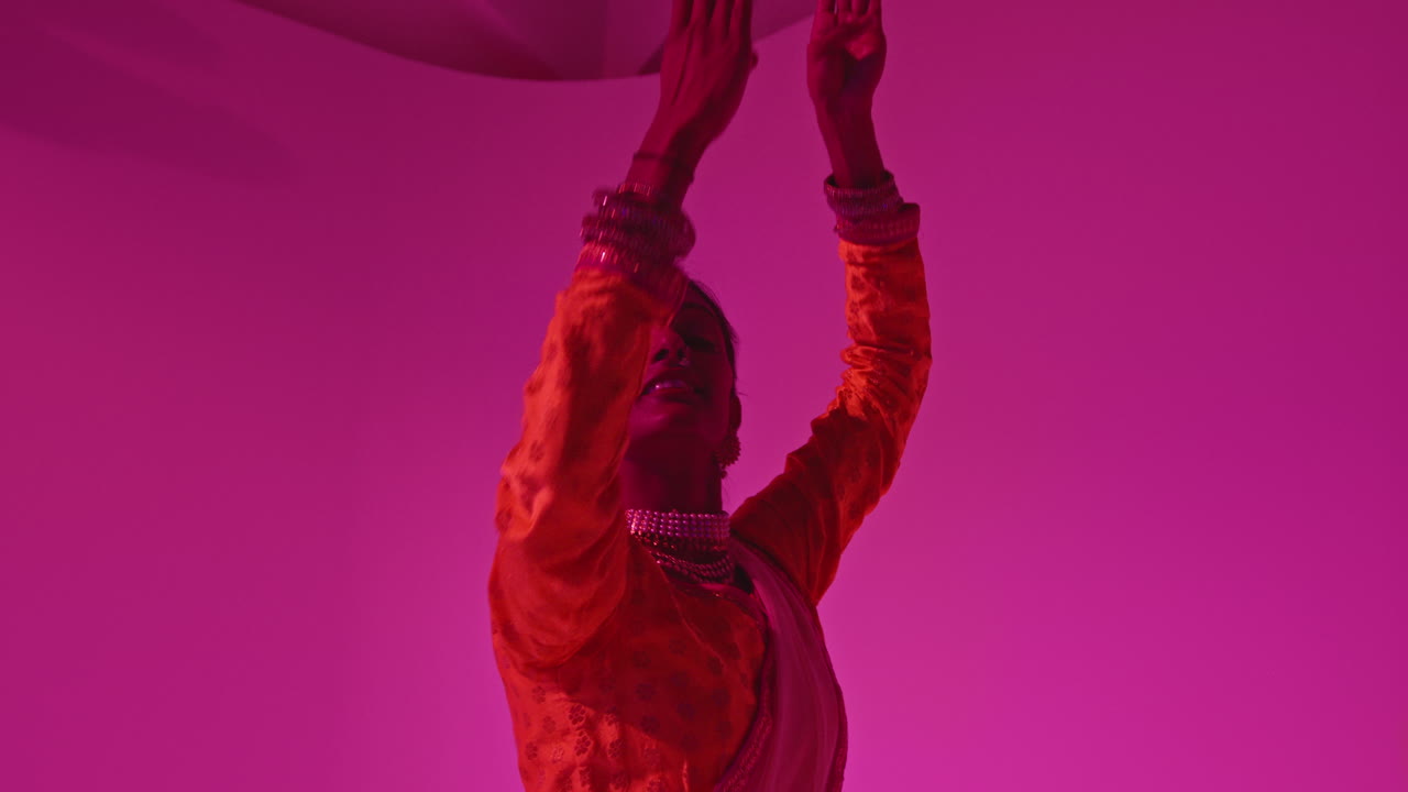 fotografía de estudio de una bailarina de kathak que realiza un baile vestida con el vestido tradicional indio contra un fondo púrpura