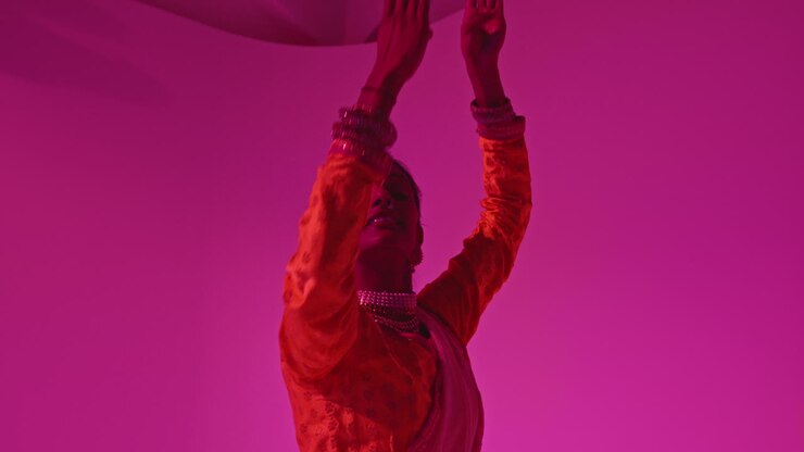 Studio Shot Of Female Kathak Dancer Performing Dance Wearing Traditional Indian Dress Against Purple Background