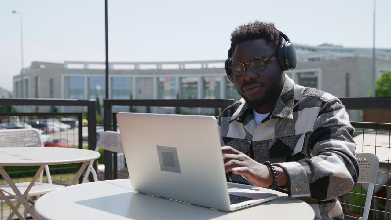 Man Working on Laptop Outdoors in Cafe