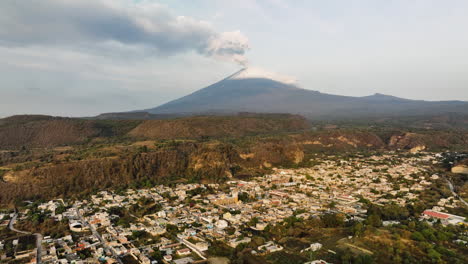 aerial view rising over a village in front of the popocatepetl volcano, in sunny mexico