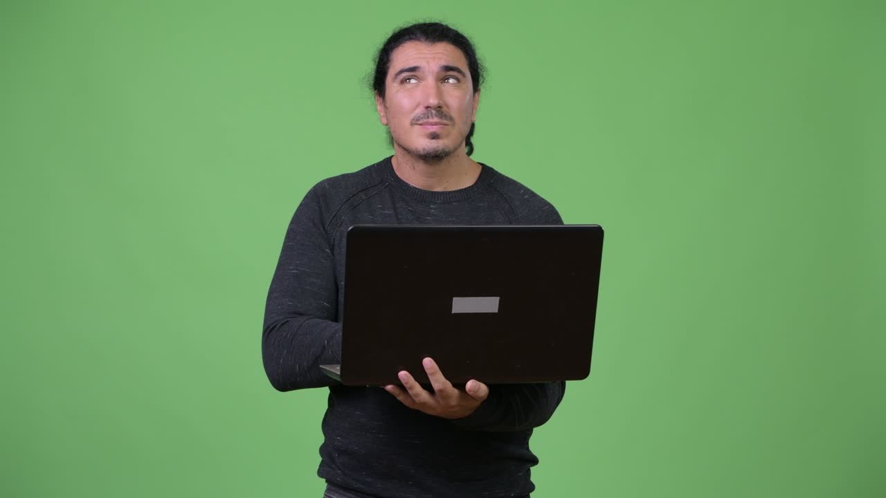 Happy handsome man thinking while using laptop