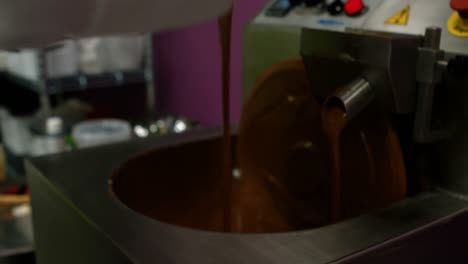 worker pouring melting chocolate in blending machine