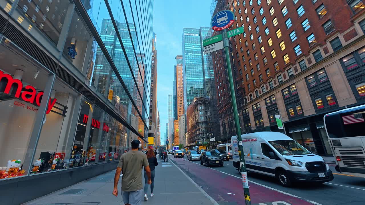 New York, USA, 7 agosto 2025: Pedone che cammina sul marciapiede di Manhattan oltre un ingresso della metropolitana. Vista posteriore di una persona che cammina su un marciapiede cittadino accanto all'ingresso di una stazione della metropolitana a New York.