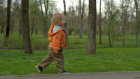 cute toddler walking in park in slow motion. small boy running outdoors