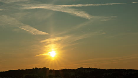 Una-Hermosa-Puesta-De-Sol,-Cuando-Se-Pone-El-Sol,-Un-Cielo-Mágico-Con-Nubes-Ligeras-Y-Un-Rastro-Del-Avión,-Pequeño-Movimiento-De-Cultivo