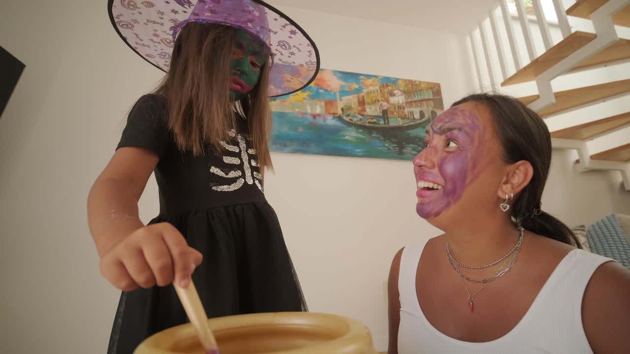 una niña vestida de bruja jugando con su madre embarazada en casa