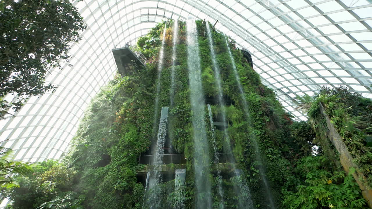 un gran invernadero de vidrio con cúpula de nubes que alberga varios