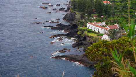 High-view-of-local-town-located-on-top-of-rocky-coastline-surrounded-by-green-lush-vegetation