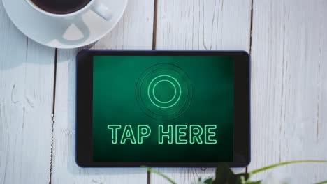 Animation-of-green-neon-style-words-Tap-Here-flickering-on-screen-of-digital-tablet-