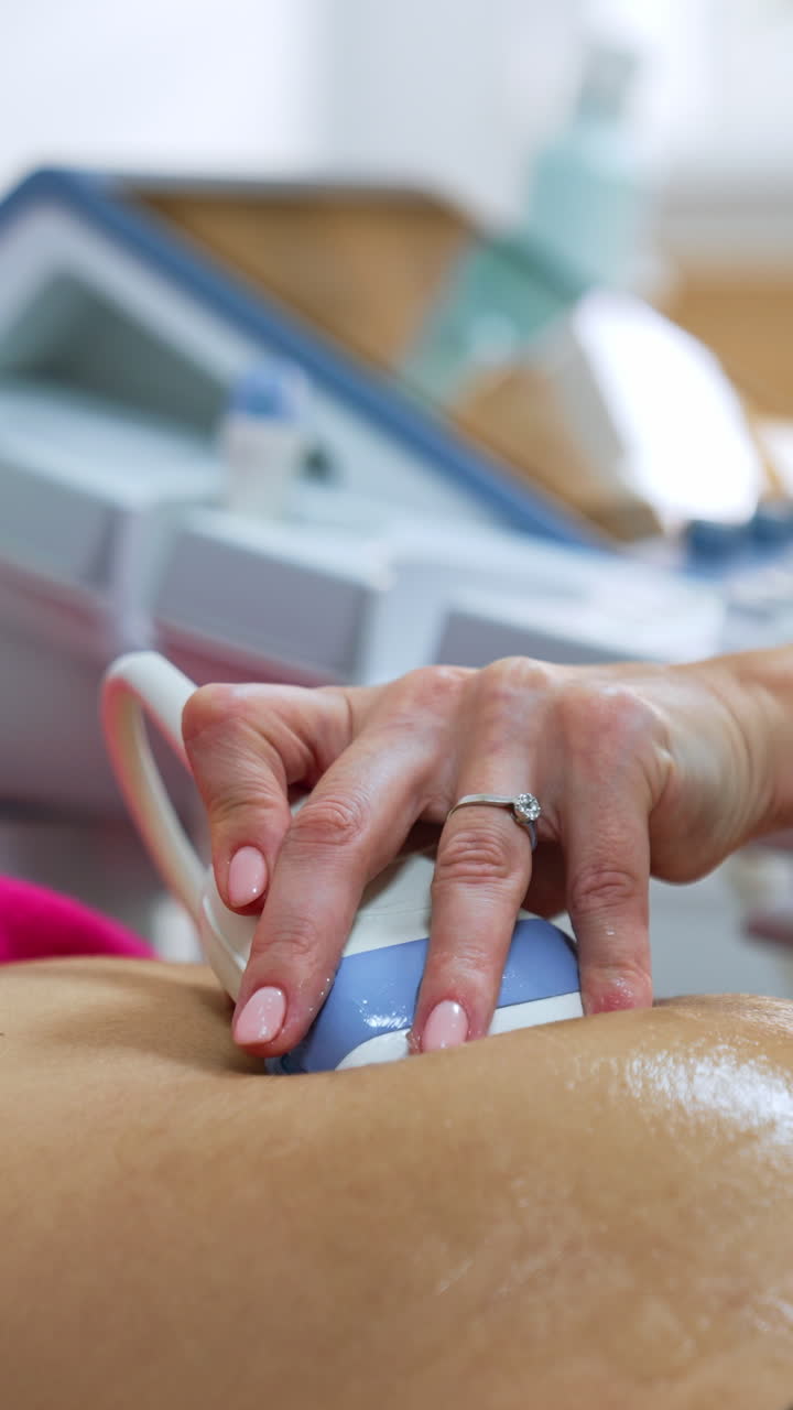 Ultrasound transducer is slowly moved by the pregnant belly of a patient. Intrauterine development of a baby check up. Vertical video