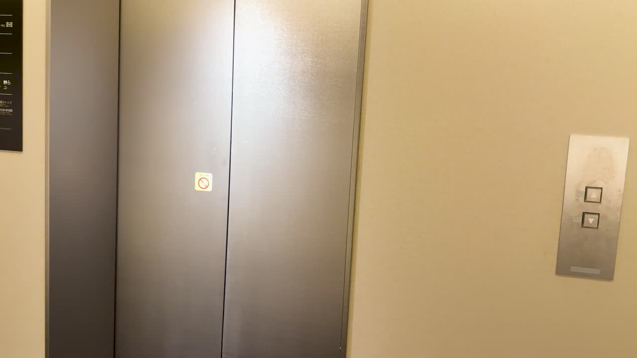 Toma estática de puertas de ascensor de acero inoxidable abriéndose en el vestíbulo de un moderno hotel japonés