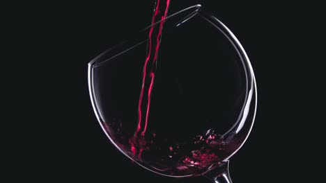 red wine in wineglass on black background