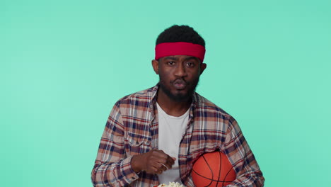 bearded african american young man basketball fan holding ball doing winner gesture, dancing alone