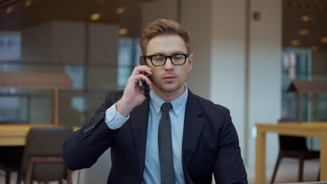 serious caucasian business man in suit talking on phone indoors - slow motion medium closeup