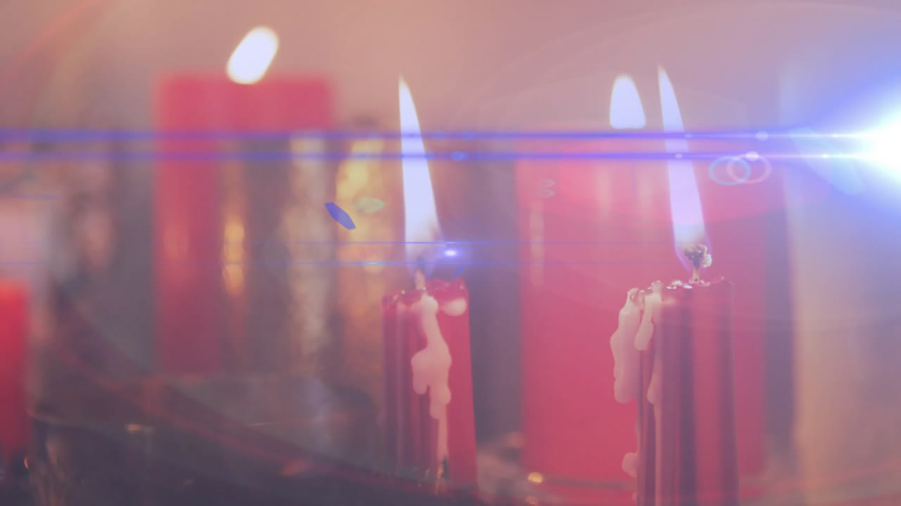 Lens flare sweeping across flickering red candles while melted wax dripping, creating warm glow