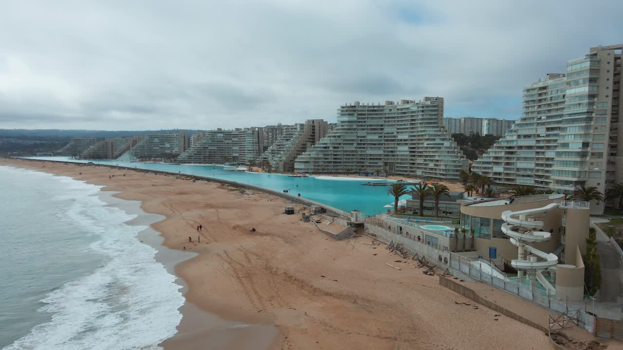 panorámica aérea a la derecha del mar y la costa de arena cerca de la piscina y resorts más grandes del mundo en algarrobo, chile