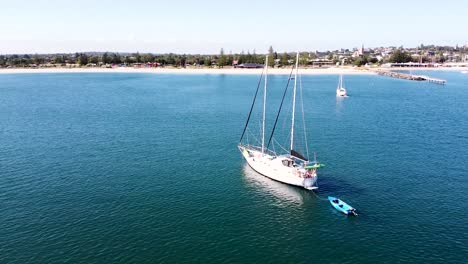 aerial - drone shot of yacht anchored off the shore of an australian town