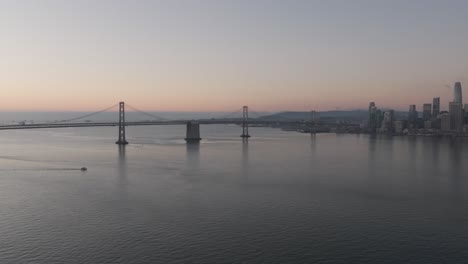 wide dawn aerial pan from oakland bay bridge to san francisco skyline at sunrise