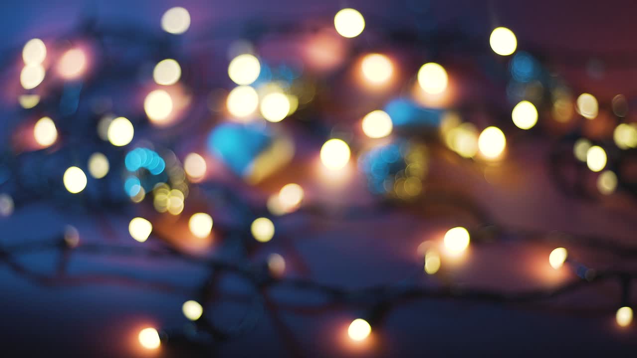 Close-up shot of garland with golden lights and christmas toys on color background. Christmas concept. Home decor. Beautiful bokeh