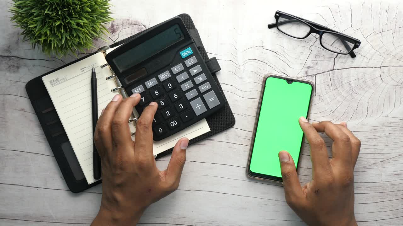Top view of man hand using smart phone and calculator on table