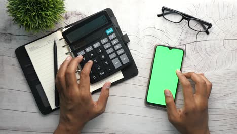 vista superior de la mano del hombre usando teléfono inteligente y calculadora en la mesa