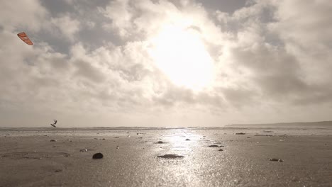 low angle beach sepia of lone person kitesurfing, getting huge aerial