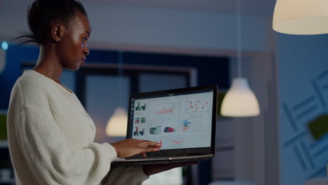 african freelancer typing on laptop late at night standing in start up office