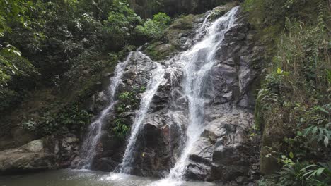 Tranquila-Cascada-De-Marinka-Que-Cae-Por-Acantilados-Rocosos-Hacia-Una-Tranquila-Piscina-En-Un-Exuberante-Bosque-Verde,-Minca