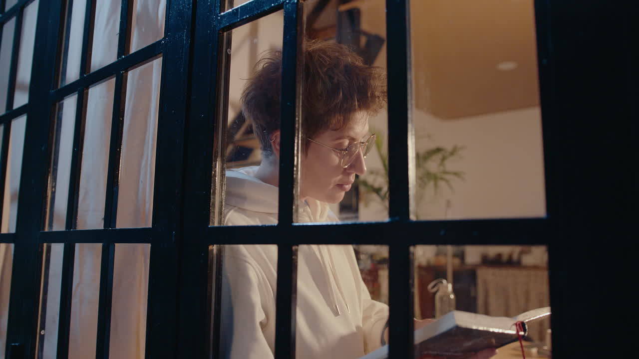Ragazza che legge un libro e guarda fuori dalla finestra la sera