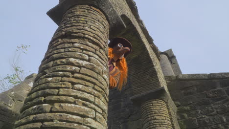 female redhead wearing plague mask appearing from behind stone archway then staring into camera