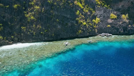 Aerial circling footage of tourist boats hover over coral reef near Matinlok shrine. El Nido, Palawan Philippines