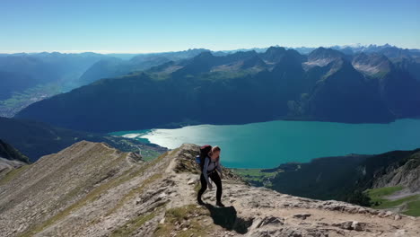 hiker on mountain ridge overlooking a scenic lake and mountain landscape
