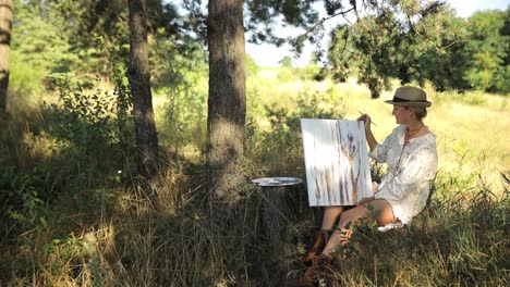 beautiful and talented artist paints a picture on an easel