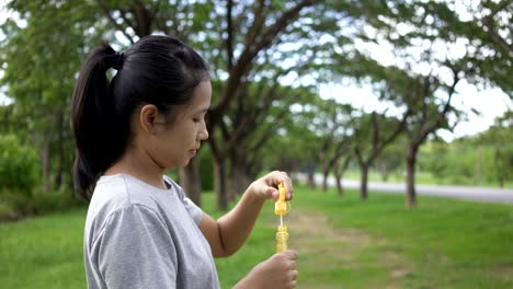 asian women happy with the activity play bubbles in the park.