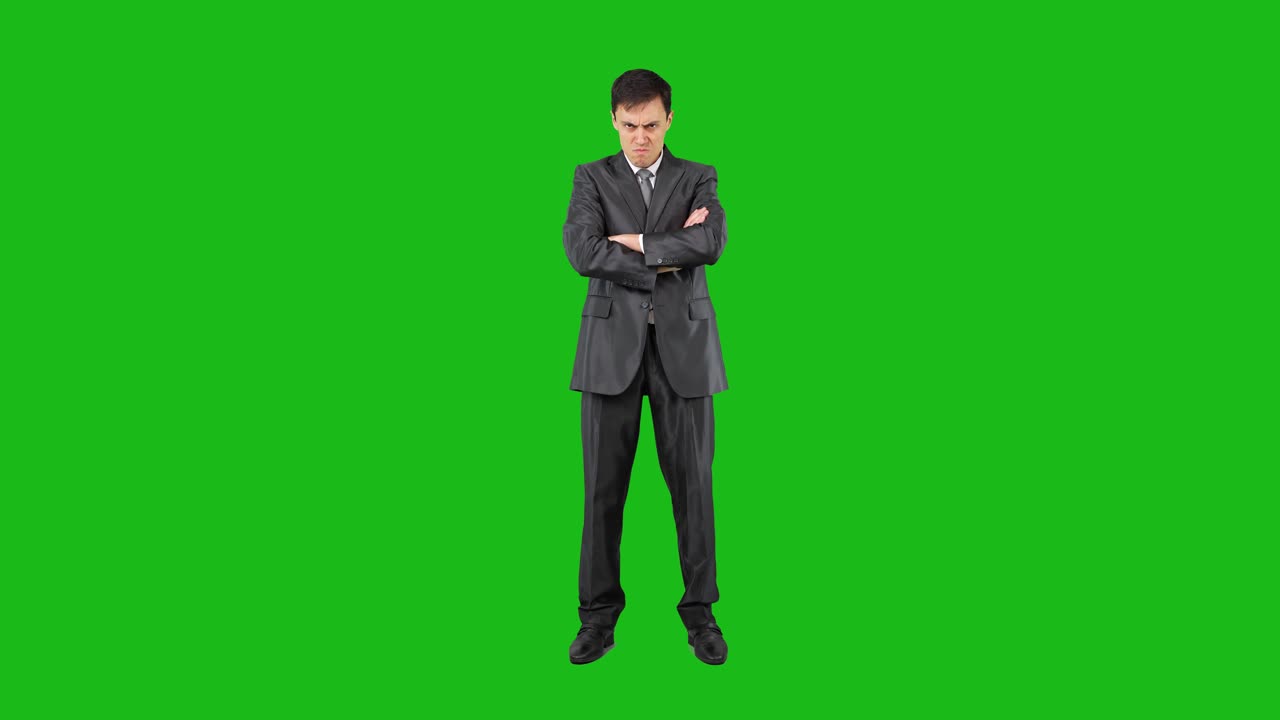 Angry businessman with crossed arms on green screen