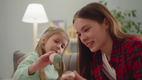 little girl with nanny prepares colored eggs with ebru art