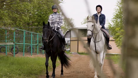 two teenagers smiling and riding horses on cloudy day