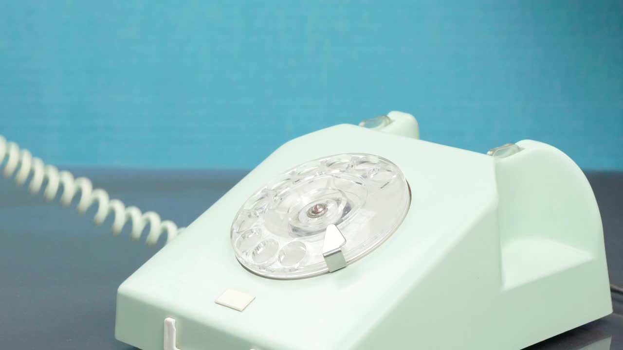 Old phone. The hand dials the number with a pen, turning the dial.