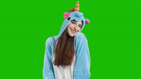 portrait of a cute young brunette girl in a beautiful unicorn costume on chrome key green background. smiling and playing. animator in costume. unicorn pajamas. 4k video with alpha channel