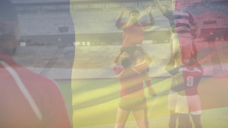 Animation-of-waving-belgium-over-team-of-diverse-male-rugby-players-playing-rugby-at-sporst-field