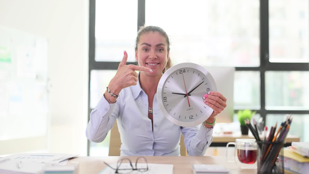 Woman pointing at a clock in an office setting