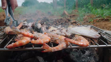 flipping shrimp on a rustic makeshift wood barbecue grill in spain, slow motion