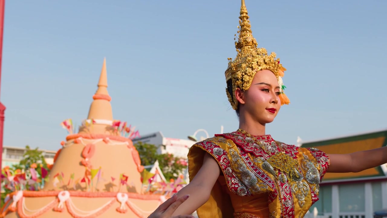 Una danzatrice classica thailandese esegue movimenti aggraziati in un tradizionale costume dorato al Wat Suthat
