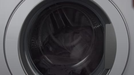 person closing washing machine door, ready to wash clothes, close up