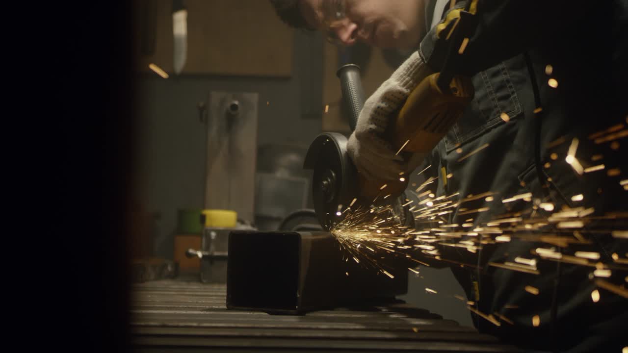 trabajador industrial cortando metal con muchas chispas afiladas. hombre usando una herramienta especial para cortar metal en el taller. chispas volando del procesamiento de metal. cámara lenta. video 4k. filmado en rojo