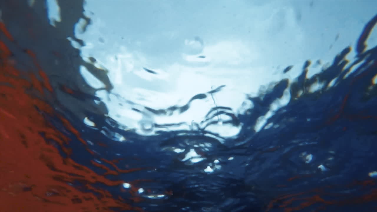Abstract and hypnotic slow motion shot of raindrops falling into a pool seen from underwater