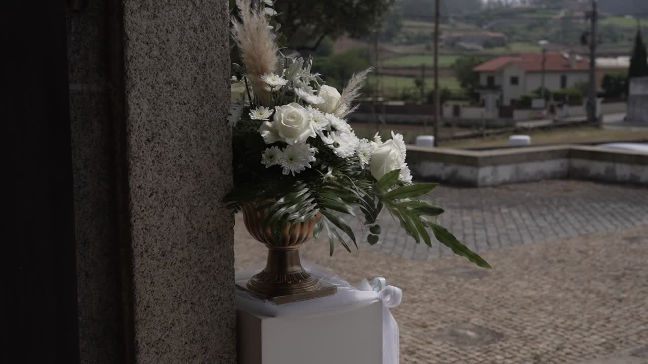 White roses and greenery in vase decorating wedding venue